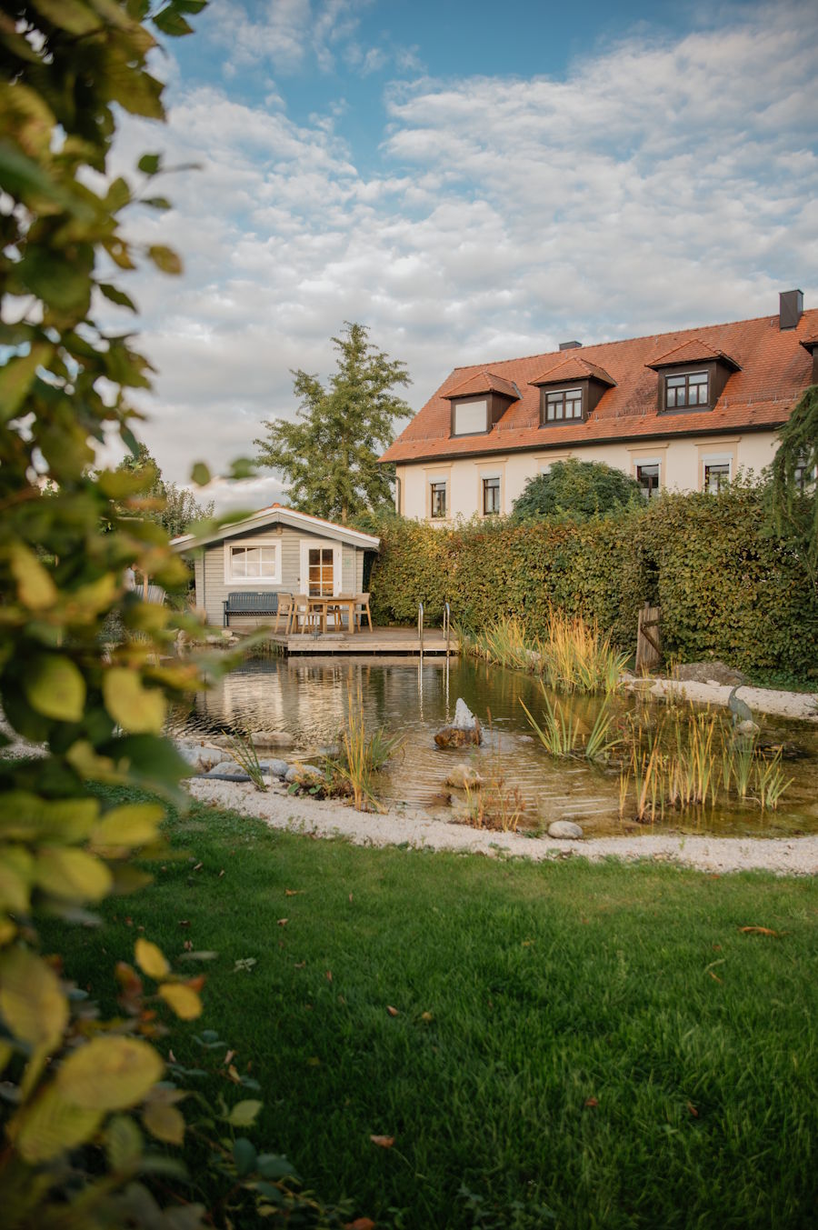 Bilderwelt Gartengestaltung - ein Blick in den Garten mit Naturteich und einem Wohnhaus im Hintergrund